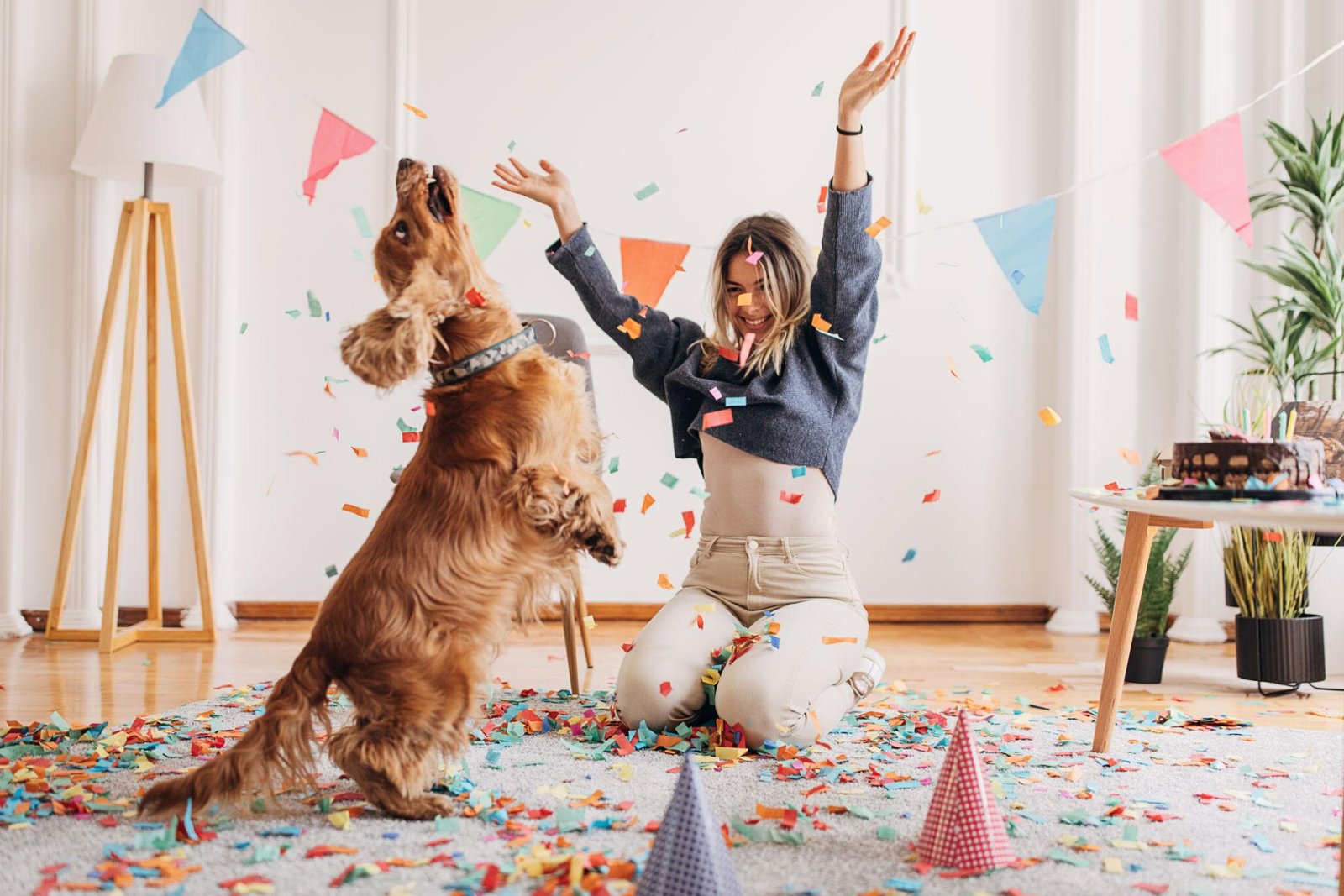 Mergina ir šuo džiaugsmingai švenčia gimtadienį kambaryje su dekoracijomis